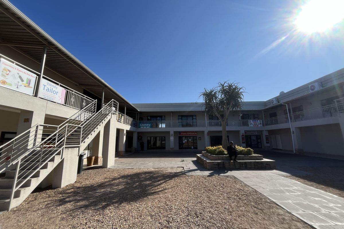 A view of the commercial courtyard featuring a central garden bed, paved walkways, and external staircases providing access to the upper level units.