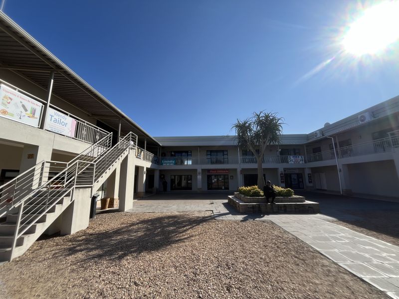 A view of the commercial courtyard featuring a central garden bed, paved walkways, and external staircases providing access to the upper level units.