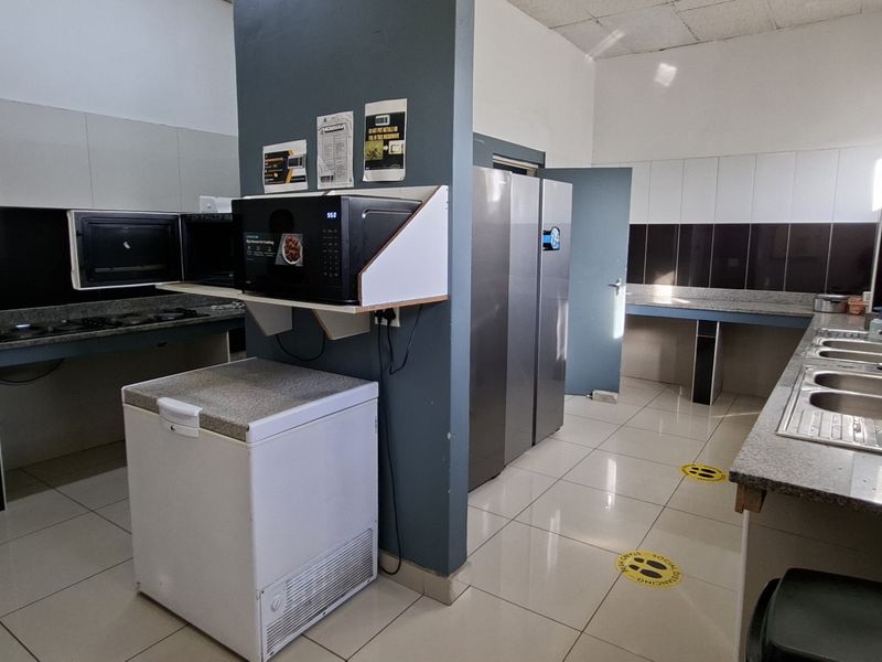 A functional kitchen area featuring granite countertops, double stainless steel sinks, and tiled backsplashes, requiring some maintenance to the ceiling and cabinetry.