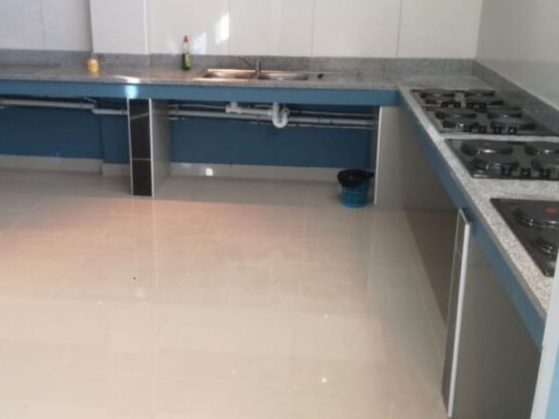 A functional kitchen featuring granite countertops, a double basin sink, and a built-in gas hob with tiled flooring and splashbacks.