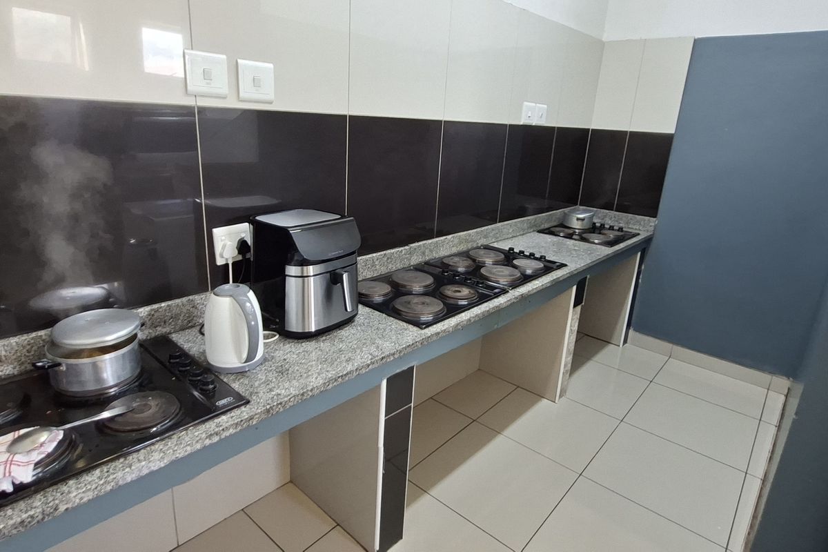 A functional kitchen area featuring granite countertops, tiled splashbacks, and multiple built-in electric hobs, providing ample workspace for cooking.