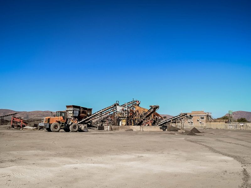 Industrial site featuring a large-scale crushing plant, conveyor systems, and associated infrastructure set within a gravel yard.