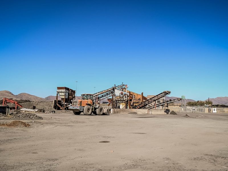 Industrial site featuring heavy crushing machinery, conveyor systems, and an expansive gravel yard, suitable for commercial or mining operations.