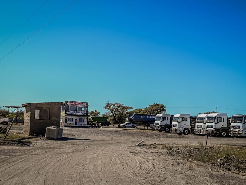Commercial truck stop facility featuring a small service building and a large gravel yard area for vehicle parking.