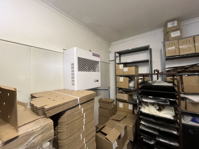 A utility storage room featuring a wall-mounted HVAC unit and industrial metal shelving for organized storage.