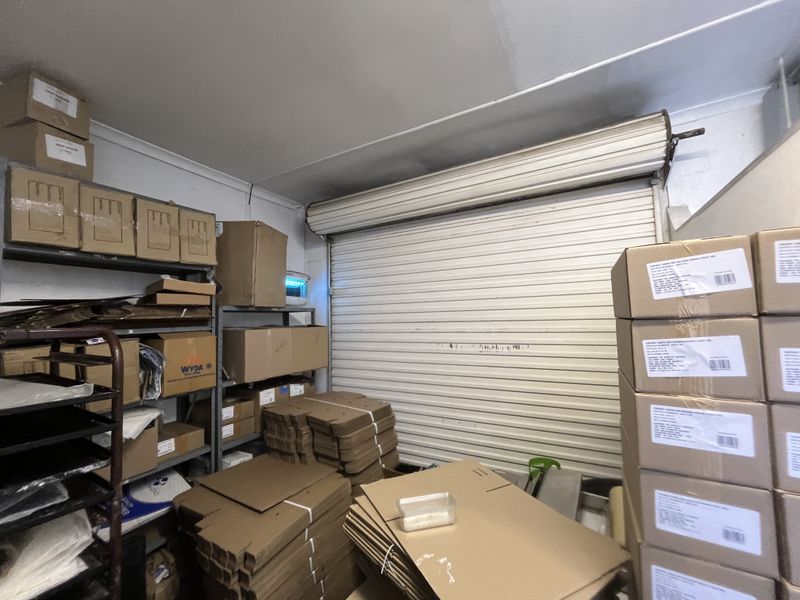 A functional utility or storage space featuring a secure roller shutter door and industrial metal shelving units for organized storage.