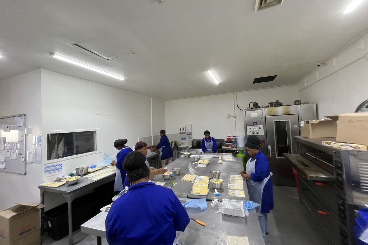 A functional commercial kitchen space featuring stainless steel preparation surfaces, industrial-grade ovens, and overhead fluorescent lighting, designed for high-volume food production.