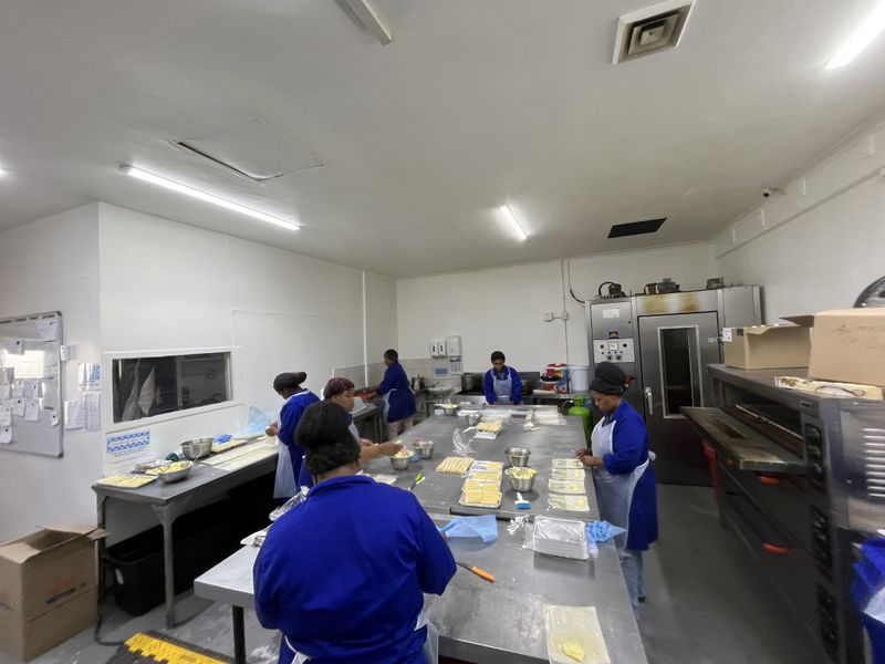 A functional commercial kitchen space featuring stainless steel preparation surfaces, industrial-grade ovens, and overhead fluorescent lighting, designed for high-volume food production.