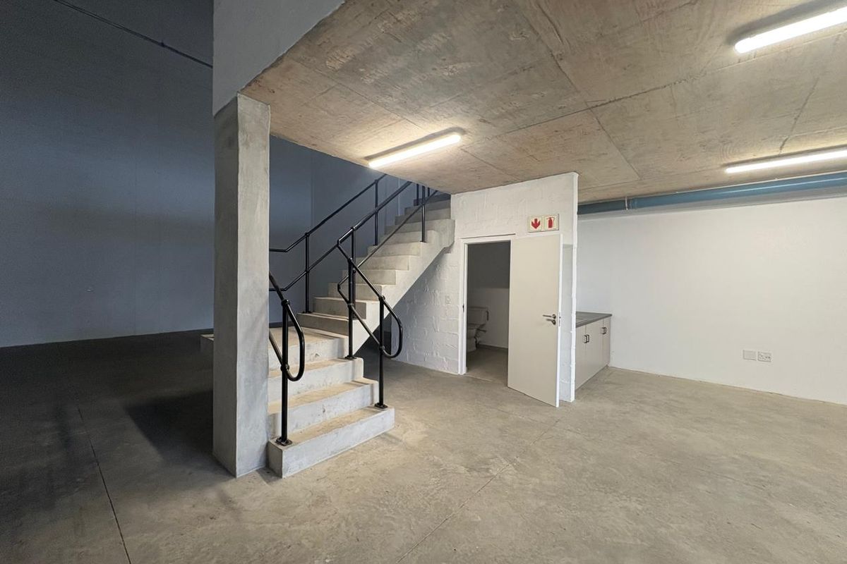 Industrial utility space featuring a concrete staircase with metal handrails, exposed concrete ceilings, built-in cabinetry, and polished concrete flooring.