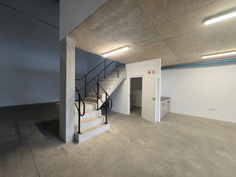 Industrial utility space featuring a concrete staircase with metal handrails, exposed concrete ceilings, built-in cabinetry, and polished concrete flooring.