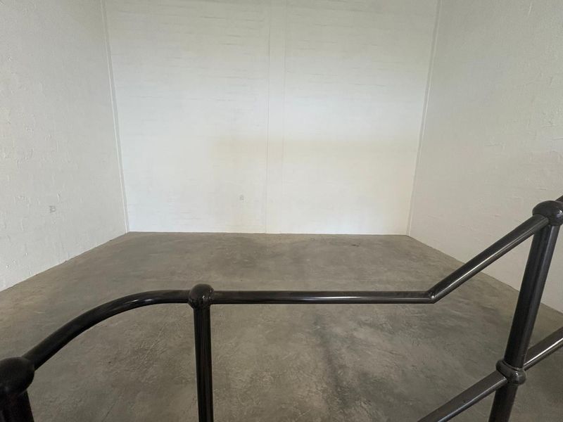 A clean, empty utility space featuring durable concrete flooring, painted brick walls, and a sturdy metal handrail.
