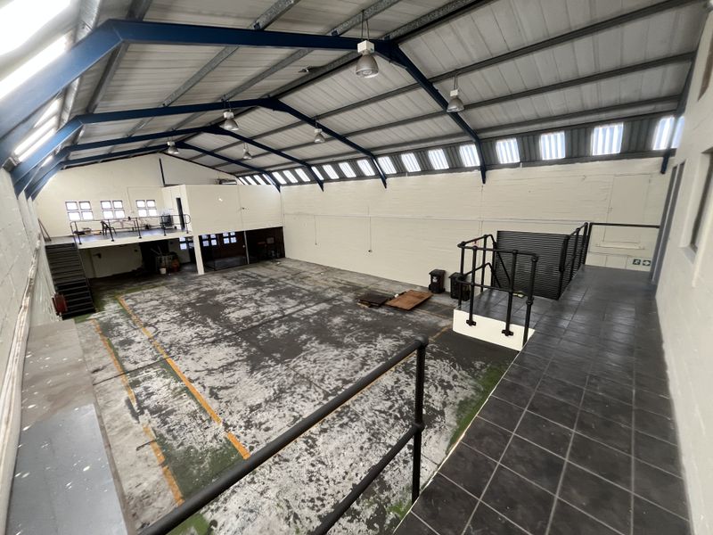 Spacious industrial warehouse featuring a mezzanine level, high ceilings with exposed steel beams, and durable concrete flooring suitable for various commercial or storage uses.