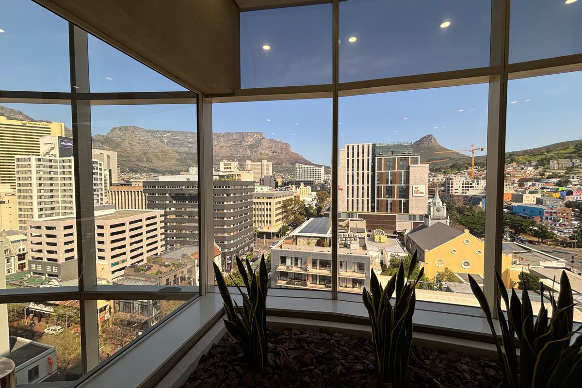 A high-level office space featuring expansive floor-to-ceiling windows with panoramic views of the city skyline and mountain range.