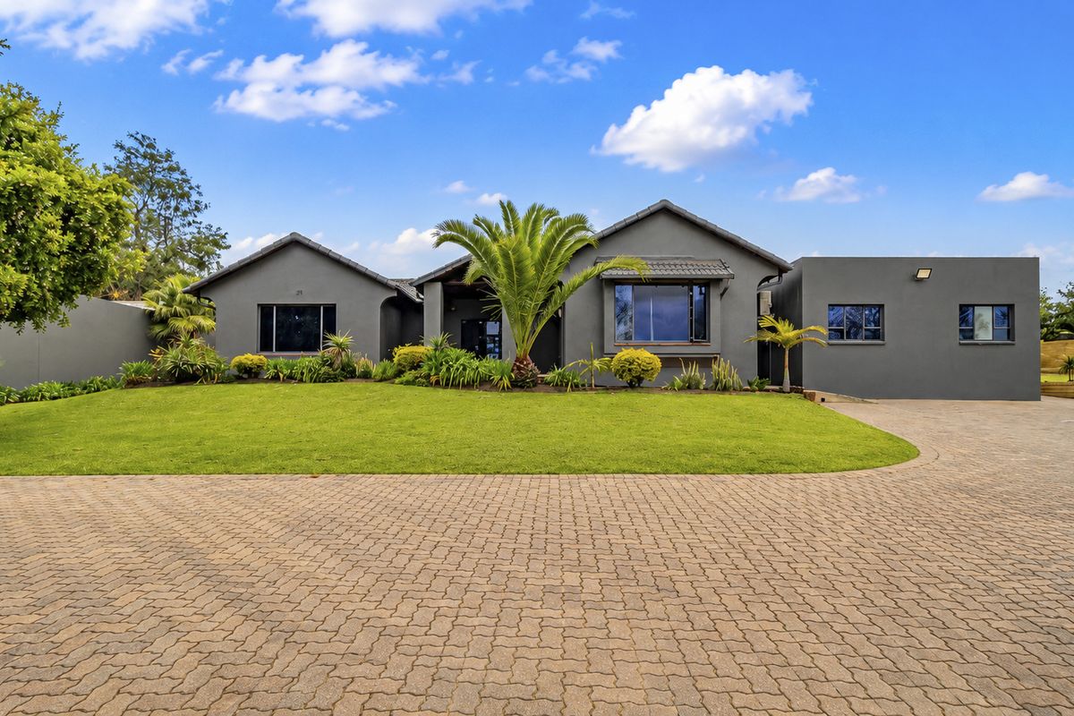 A well-maintained front elevation of an office property featuring a paved driveway, manicured lawn, and modern grey exterior finish.
