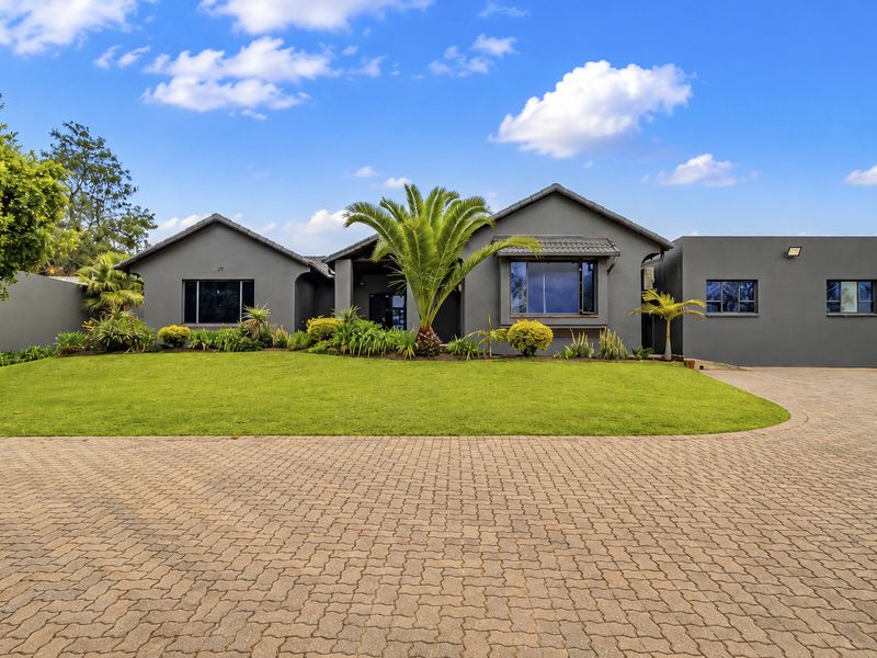 A well-maintained front elevation of an office property featuring a paved driveway, manicured lawn, and modern grey exterior finish.