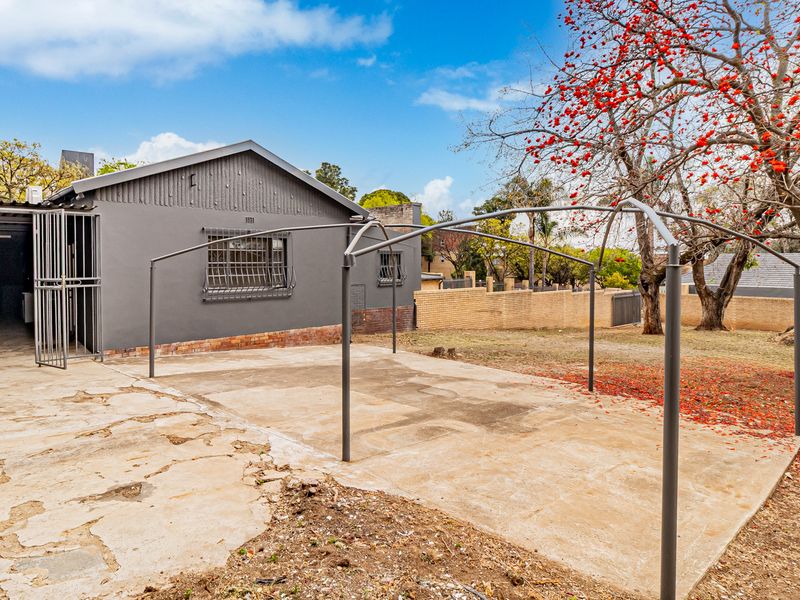 Rear exterior view of the office property featuring a concrete patio area, security bars on windows, and a brick boundary wall.