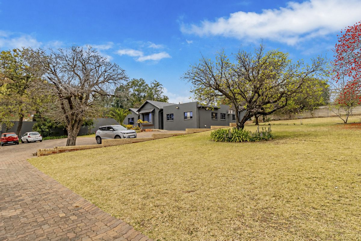 Front view of the office property featuring a paved driveway, landscaped garden, and a well-maintained building exterior with a tiled roof.
