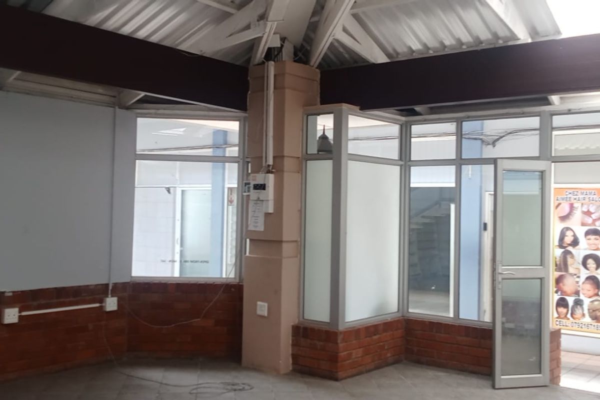 Open-plan retail space featuring exposed roof trusses, brick base wall detailing, and extensive aluminium-framed glass frontage for high visibility.