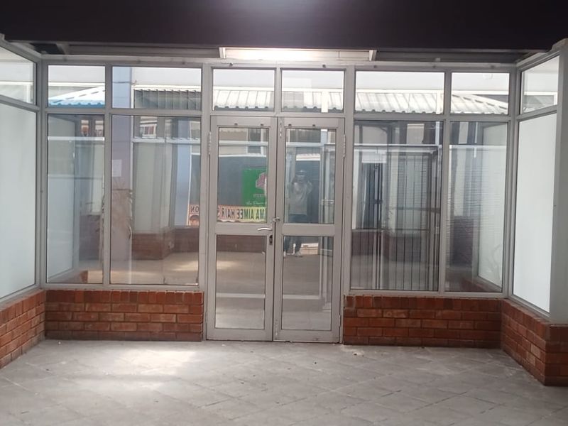 A retail storefront entrance featuring aluminium-framed glass doors and windows with a brick base, providing a clear view into the vacant commercial space.