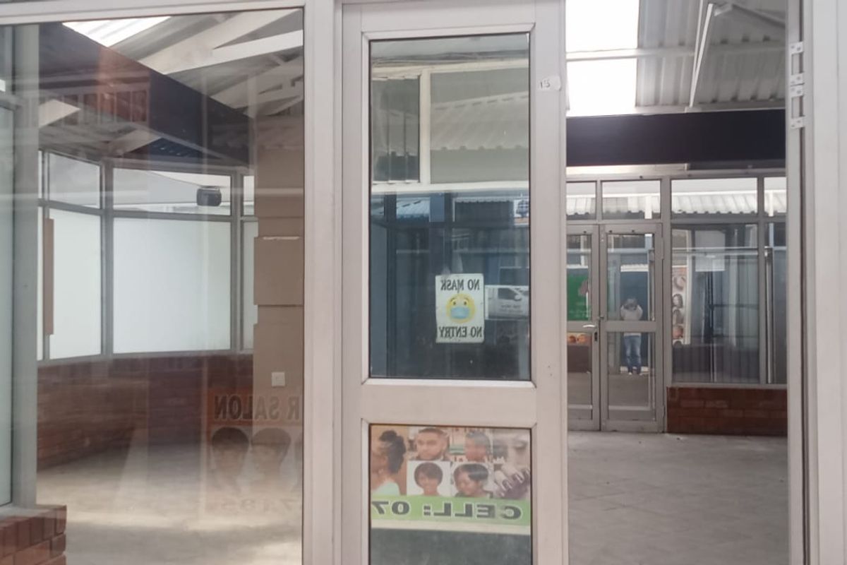 A vacant retail entrance featuring aluminium-framed glass doors and windows with a brick base, providing a bright and open storefront space.