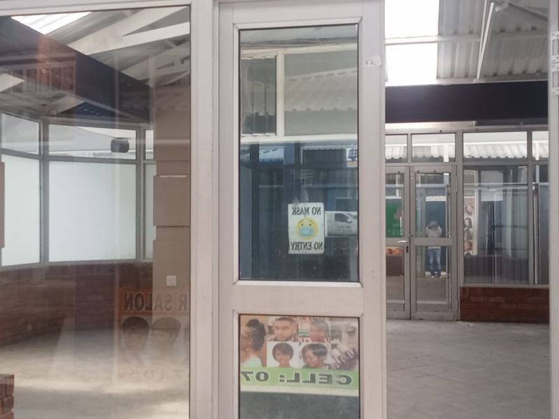 A vacant retail entrance featuring aluminium-framed glass doors and windows with a brick base, providing a bright and open storefront space.