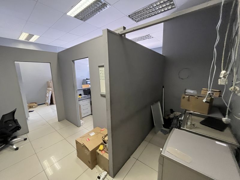 An office space featuring partitioned rooms, tiled flooring, and suspended ceiling lighting, currently showing signs of wear and requiring maintenance.