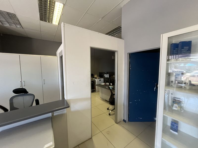 Office space featuring tiled flooring, suspended ceiling with integrated lighting, and partition walls creating a functional workspace layout.
