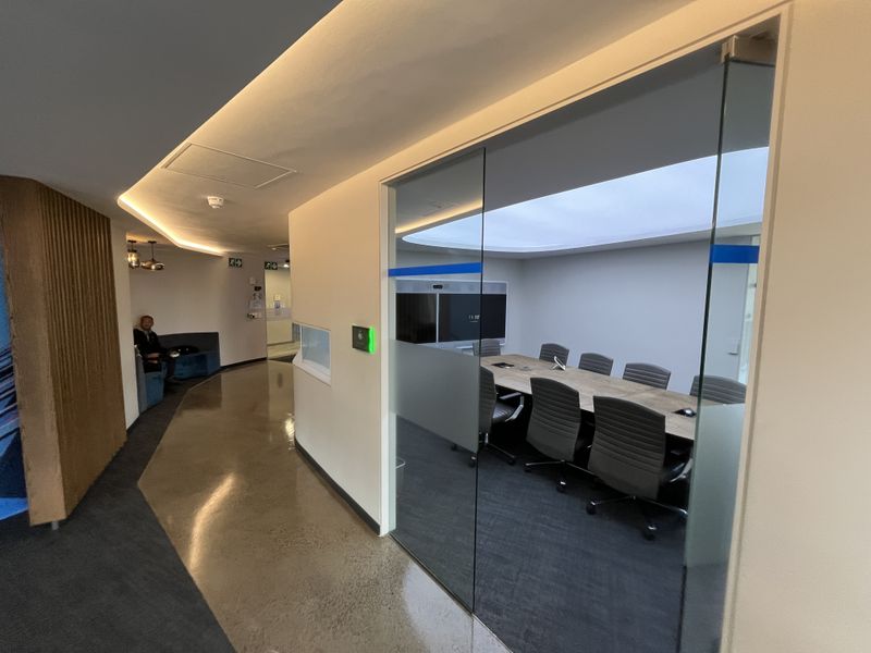 Modern office meeting room featuring a glass partition wall, polished concrete flooring, and integrated ceiling lighting, providing a professional and contemporary workspace environment.