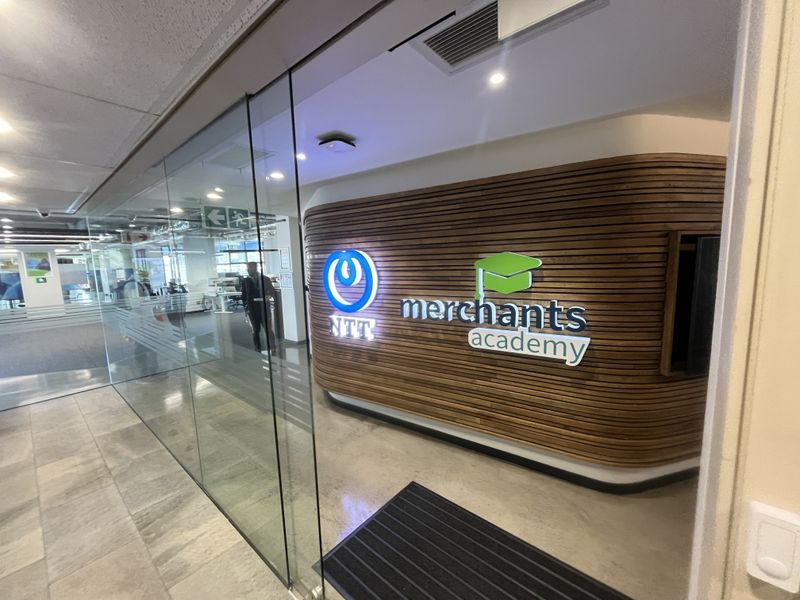 Modern office entrance featuring a glass partition wall and a prominent slatted timber feature wall with corporate branding.