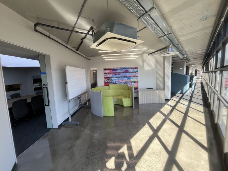Modern open-plan office space featuring polished concrete floors, exposed industrial ceilings, and large windows providing ample natural light.