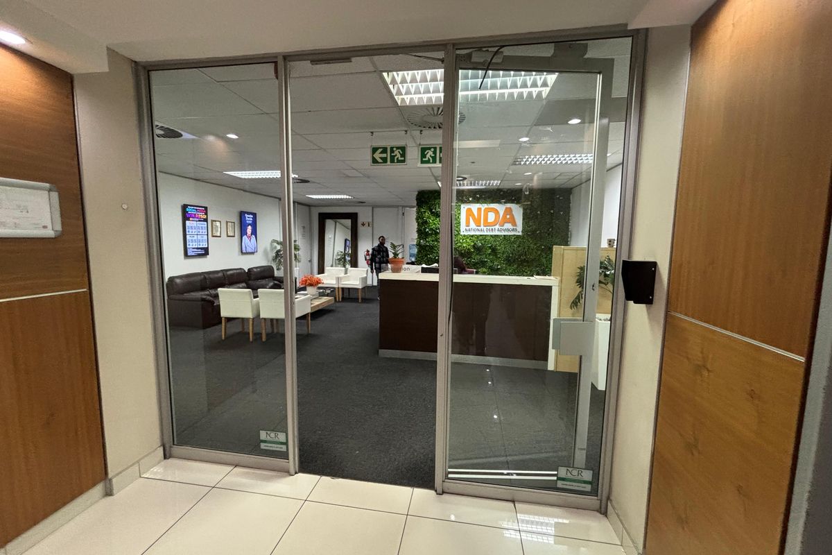 Professional office reception area featuring a glass entrance, reception desk, and a decorative feature wall, providing a welcoming entry point for clients.