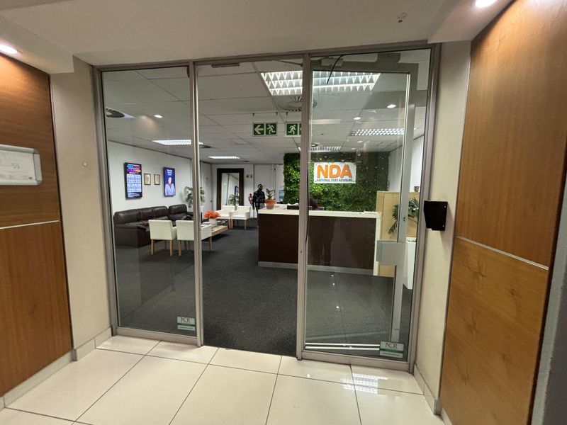 Professional office reception area featuring a glass entrance, reception desk, and a decorative feature wall, providing a welcoming entry point for clients.