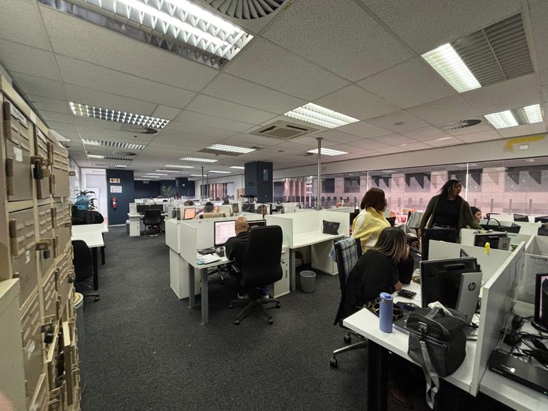 Open-plan office space featuring suspended ceilings, recessed lighting, integrated air conditioning, and built-in storage lockers.