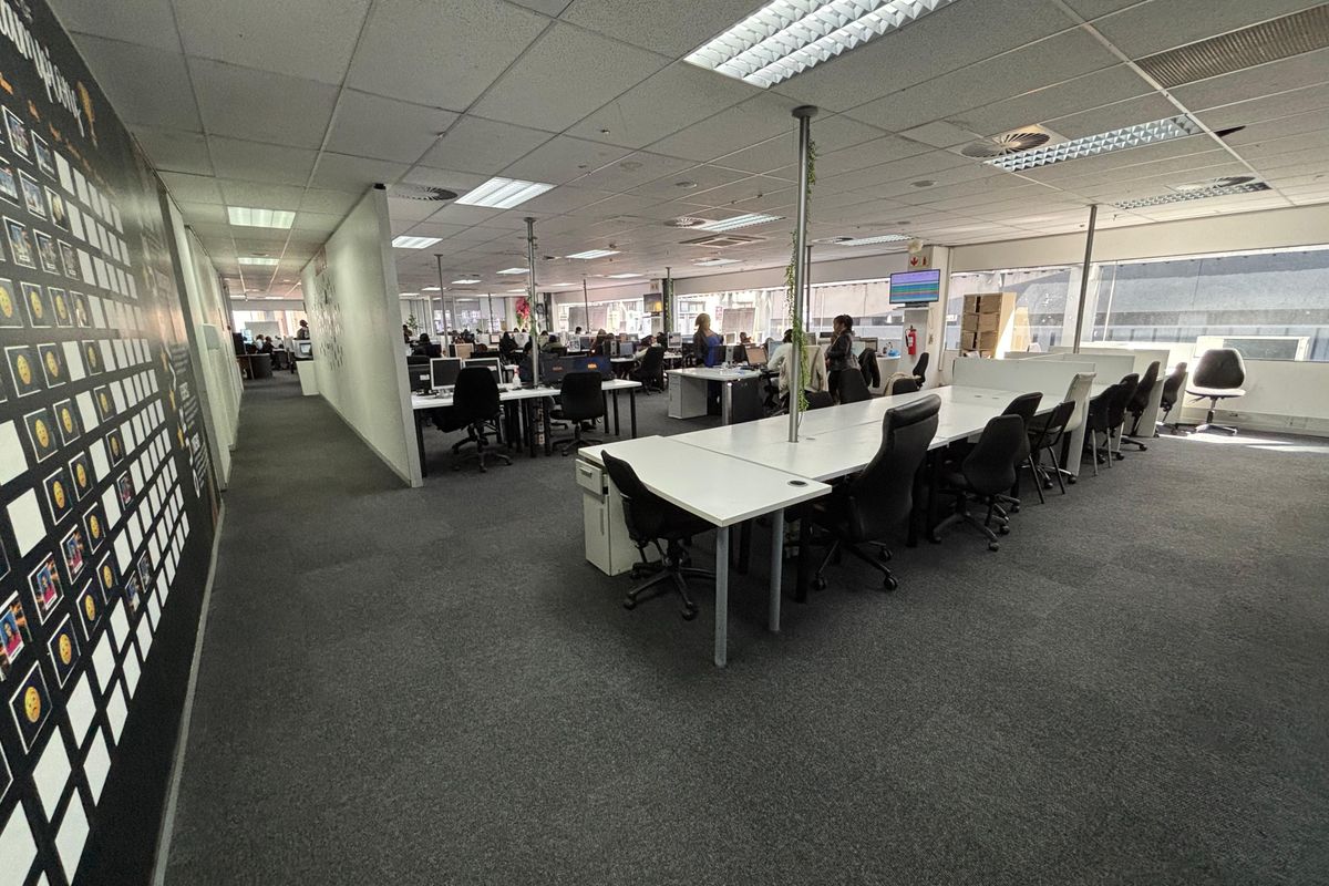 Spacious open-plan office area featuring suspended ceilings, recessed lighting, and carpeted flooring, providing a functional workspace environment.