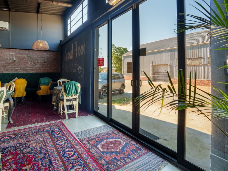 A dining area in a restaurant featuring exposed brick walls, high ceilings with exposed beams, and large glass sliding doors providing natural light.