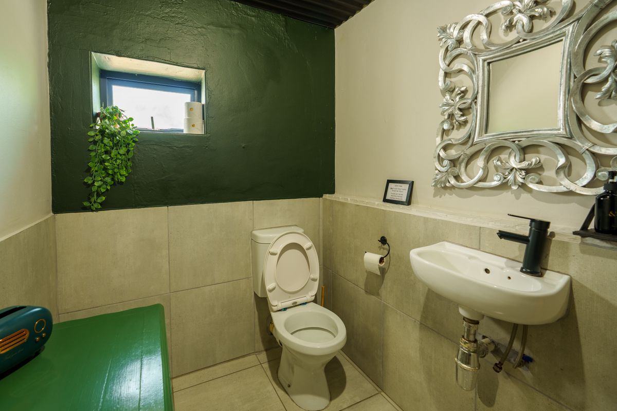 A compact restaurant restroom featuring tiled walls, a wall-mounted basin with a modern black tap, and a standard toilet.