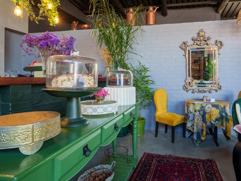 A charming dining area featuring exposed timber ceiling beams, painted brick walls, and polished concrete flooring, creating a warm and inviting atmosphere.