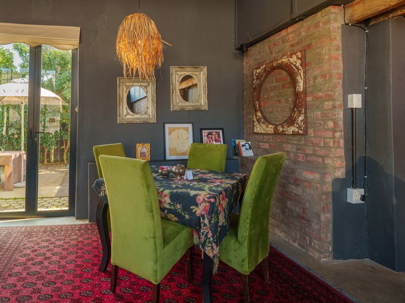 A dining area featuring an exposed brick feature wall, dark painted walls, and a large glass sliding door providing access to the outdoor patio.
