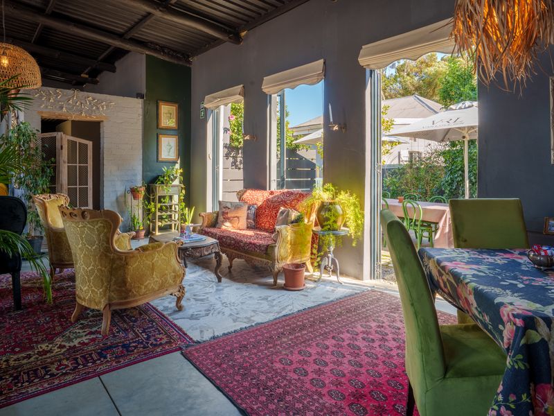 Spacious open-plan restaurant area featuring exposed beam ceilings, polished concrete floors, and large bi-fold doors opening to an outdoor patio space.