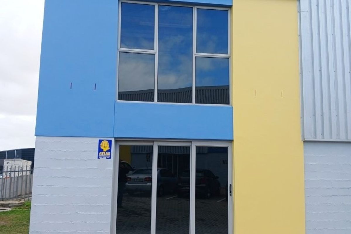 Front facade of a modern office building featuring blue and yellow painted panels, corrugated metal siding, and large aluminium-framed windows and sliding doors.