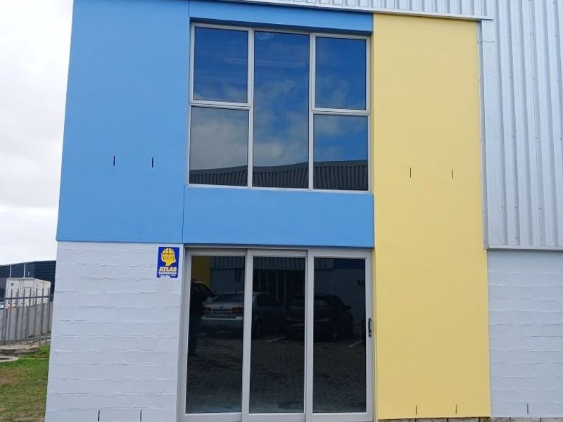 Front facade of a modern office building featuring blue and yellow painted panels, corrugated metal siding, and large aluminium-framed windows and sliding doors.