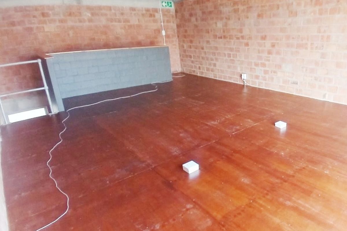 An empty office space featuring exposed brick walls, exposed ceiling beams, and basic utility finishes, suitable for custom fit-out.