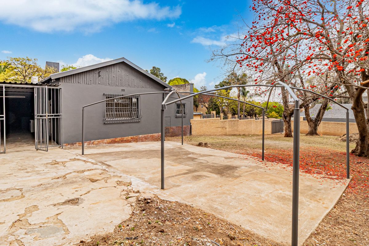 Rear exterior view of the office property featuring a concrete patio area, security bars on windows, and a brick boundary wall.