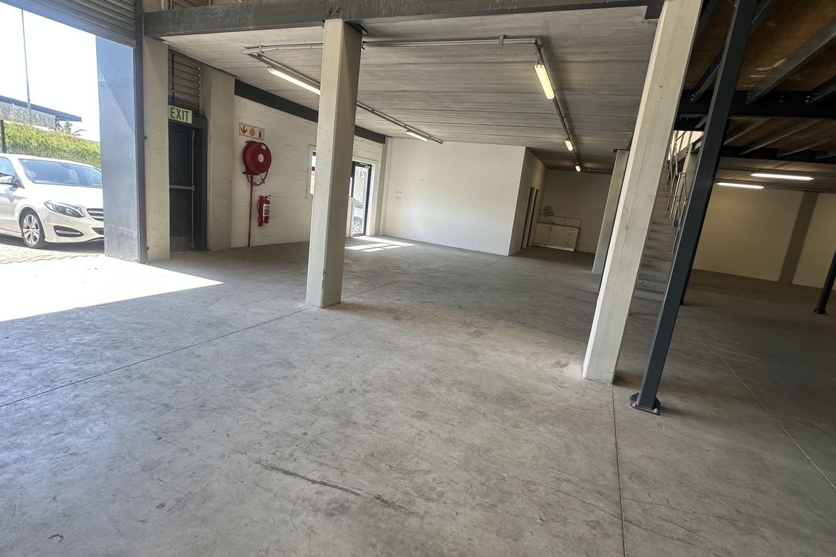 Spacious industrial utility area featuring concrete flooring, a steel mezzanine level, and integrated fire safety equipment with direct roller shutter access.