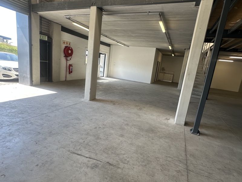 Spacious industrial utility area featuring concrete flooring, a steel mezzanine level, and integrated fire safety equipment with direct roller shutter access.