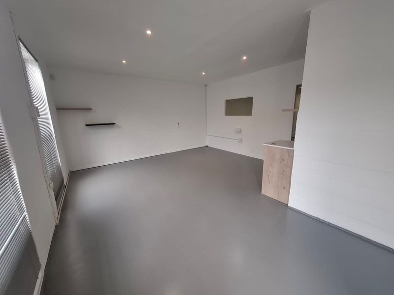 A clean, open-plan industrial space featuring smooth epoxy flooring, recessed downlighting, and a built-in counter, offering a versatile layout for various business needs.