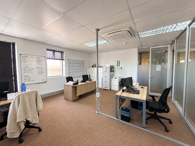 A functional office space featuring suspended ceilings, recessed lighting, integrated cassette air conditioning, and glass partition walls, providing a professional work environment.