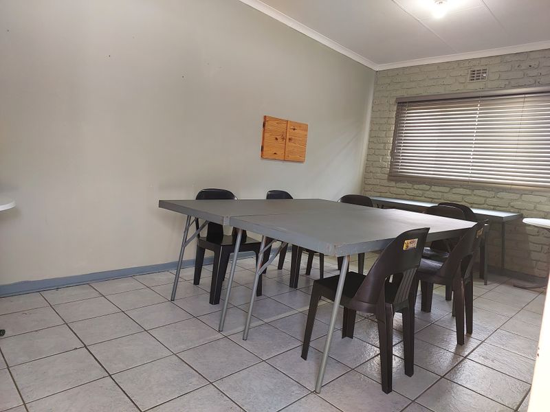 A functional office space featuring tiled flooring, a painted brick feature wall, and venetian blinds, providing a practical environment for professional use.