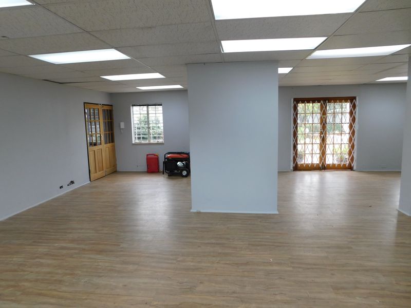 Spacious open-plan office area featuring laminate flooring, recessed lighting, and secure timber-framed access doors.