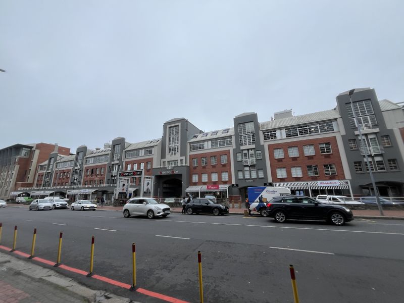 Street-level view of the Sovereign Quay office complex, featuring a multi-story brick and grey facade with ground-floor commercial access.